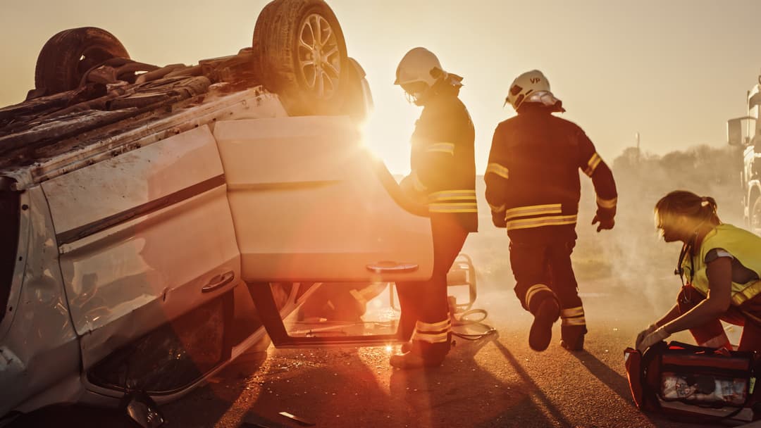 Some firefighters standing in front of a crashed car